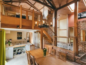 Ein geräumiger Innenraum im Loft-Stil mit Küche, Essbereich und einer Treppe, die in einen oberen Bereich führt.