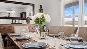 A dining area with a wooden table set for six, a vase with flowers, and a wine bottle. - The Lake House on Boyd Private Boat Ramp & Dock (Loveland)