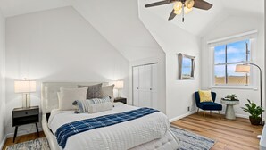 A bedroom with a bed, nightstands, a ceiling fan, a window, and a chair. - The Lake House on Boyd Private Boat Ramp & Dock (Loveland)