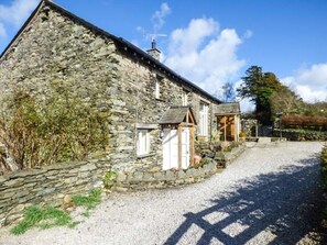 A stone building with a gravel driveway and a wooden structure attached. - Kestrel Cottage, Cartmel (Grange-Over-Sands)
