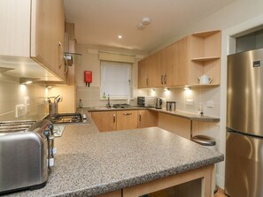 Una cocina moderna con encimeras de granito, electrodomésticos de acero inoxidable y armarios de madera.