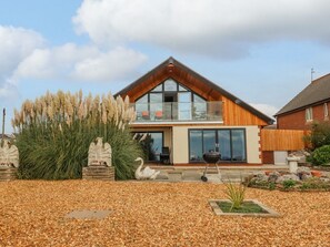 A modern two-story house with a large balcony, a barbecue grill, and decorative swan statues in the garden. - Sea La Vie, Lytham St. Annes (Lytham St. Annes)