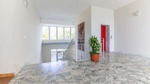 Ein geräumiger Innenraum mit Marmorboden, einer Treppe, einer roten Tür und einem Blumentopf.
