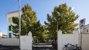 Ein begrenzter Zugang mit einem Verbotsschild, ein Fahrrad, das neben dem Tor steht, und ein Gebäude mit weißer Fassade und grünen Fensterläden.