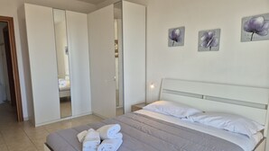 Ein Schlafzimmer mit Bett, Kleiderschrank und Spiegel.