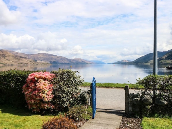 A pathway leading to a body of water with mountains in the background.