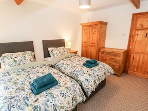 Une chambre avec deux lits, une armoire en bois et une table de chevet avec une lampe.