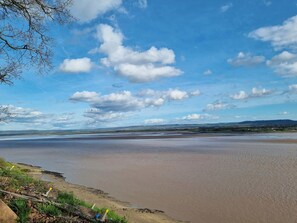 A wide, flat beach with a clear sky and distant hills.