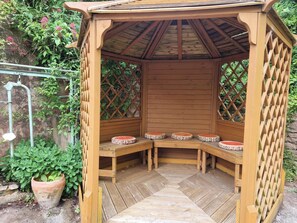 A wooden gazebo with a sloped roof and a lattice design.