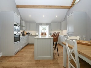 Une cuisine moderne avec des meubles blancs, un îlot central et une table à manger en bois.