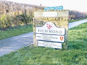 Een bord met 'Richmond' en informatie over de zusterstad, een bord met 'Gratis Schijf Parkeren' en een pad.