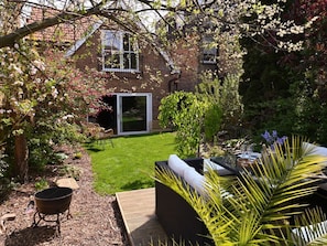 Ein Garten mit Grill, Gartenmöbeln und einem Haus im Hintergrund.