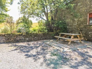 A stone wall, a wooden picnic table, and a gravel area with trees and shrubs. - Westfield Cottage, Mickleton, Teesdale (Barnard Castle)