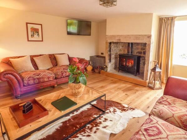 Una sala de estar acogedora con sofá, una mesita de centro, chimenea y un tapiz de cuero de vaca.
