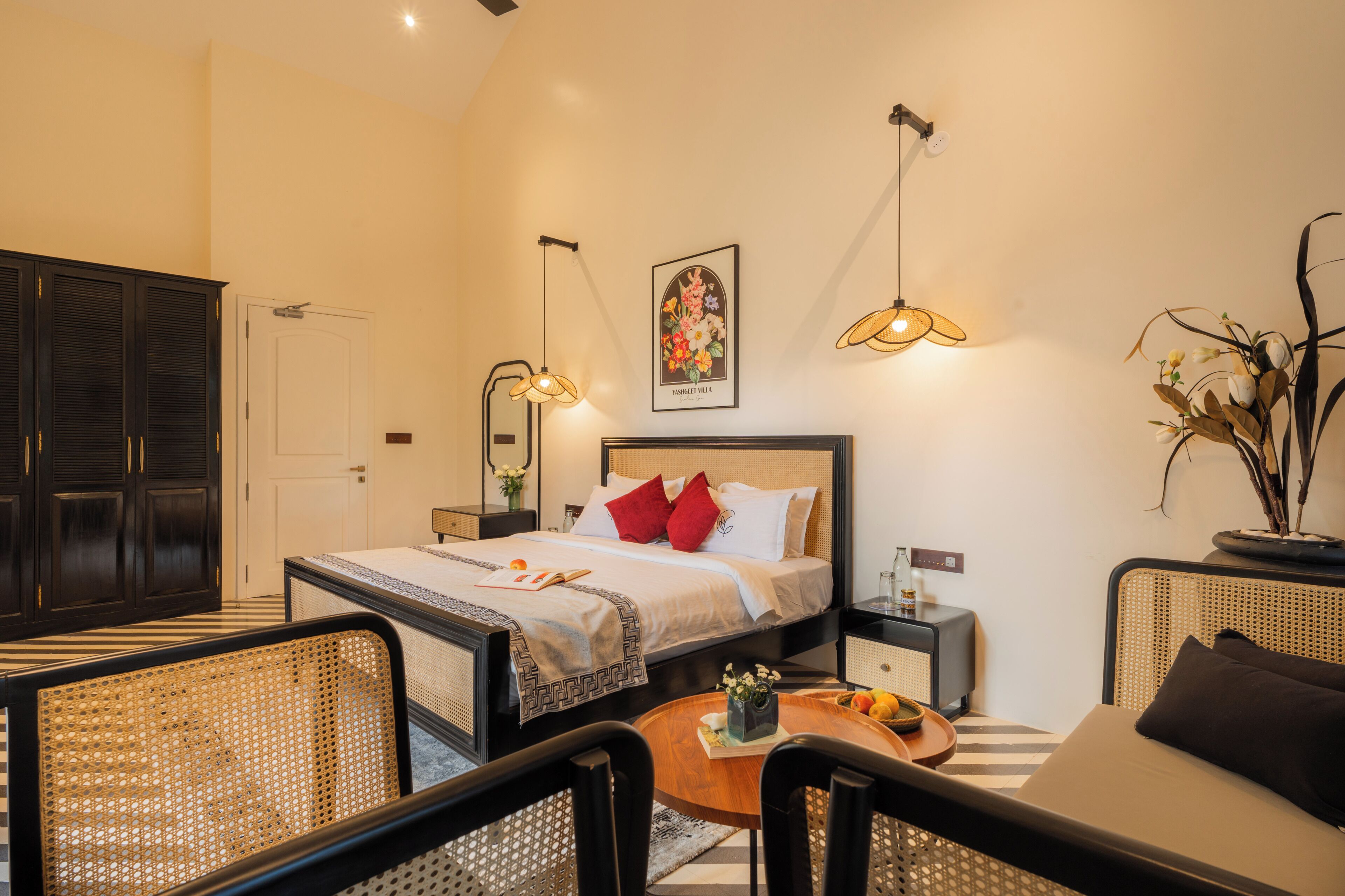 A bedroom with a bed, bedside tables, a chair, a small table with a tray, and a potted plant.