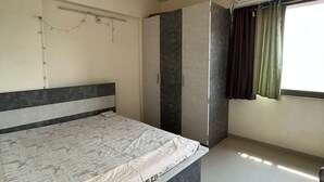 Quarto com cama, ventoinha no teto, ar condicionado, guarda-roupa e janela com cortinas.