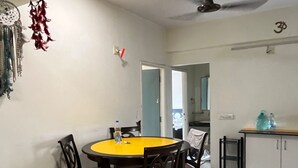Uma sala de jantar com uma mesa redonda, cadeiras, um ventilador de teto e um adorno de pena pendurado na parede.