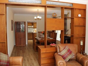 Una habitación con sofá de madera, una mesa de comedor y una zona de cocina.