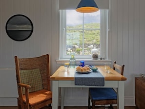 Un comedor con una mesa, sillas, un ventanal con vistas y una lámpara colgante.