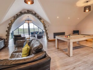 A cozy loft room with a leather sofa, a pool table, and a stone archway.