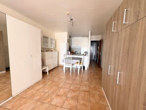 A modern kitchen with white cabinets, a dining table, and chairs. - Studio sea view, AC, pets welcome - 2 guests (Le Barcarès)