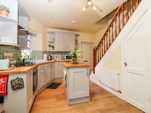A kitchen with white cabinets, a wooden countertop, a built-in oven, and a staircase with wooden railings.