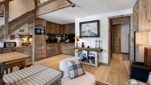 Un amplio salón con techo alto, vigas de madera, una cocina con electrodomésticos modernos y una zona de estar acogedora.