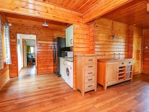 L’intérieur d’une cabane en bois, avec un lave-linge, un réfrigérateur et un évier.