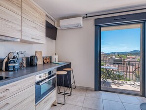 Eine moderne Küche mit einem großen Fenster, einem Balkon und Blick auf die Stadt.