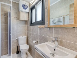 Ein Badezimmer mit Toilette, Waschbecken, Dusche und Fenster.