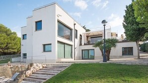 Un bâtiment moderne à deux étages, doté d’un toit plat, de grandes fenêtres et d’un mur de soutènement en pierre.