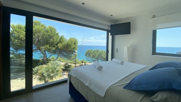 Une chambre avec une grande fenêtre, un lit et une vue sur la mer.