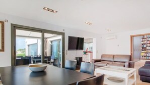 Un salon moderne comprenant un coin repas, un canapé, une table basse et un téléviseur.
