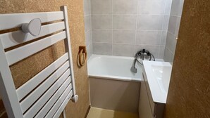 Een badkamer met een wit bad, een witte wastafel en een handdoekhouder.