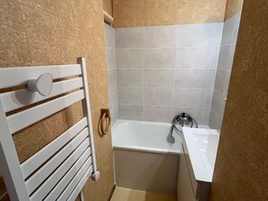 A bathroom with a white bathtub, a white sink, and a towel rack. - Renovated studio near Châtel ski lifts (Châtel)