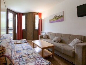 Ein Wohnzimmer mit einer Couch, einem Holztisch und einem beigefarbenen Sofa.