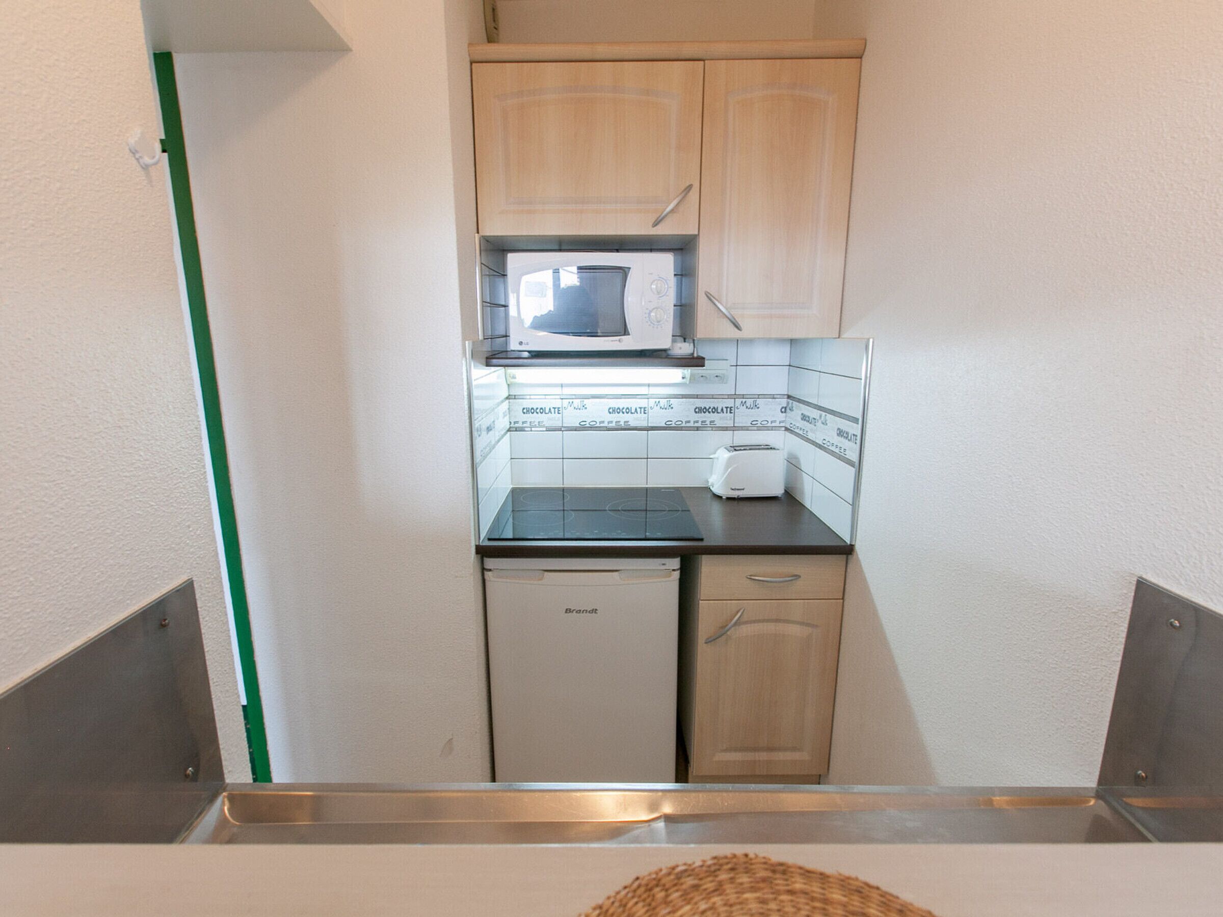 Eine kleine Küche mit Mikrowelle, Toaster und kleinem Kühlschrank.