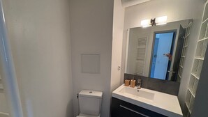 Ein Badezimmer mit Toilette, Waschbecken, Spiegel und Handtuchhalter.