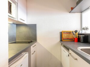 A kitchen with white cabinets, a microwave, a stove, and a sink. - Cozy apartment with ski locker - 5 guests (Avoriaz)
