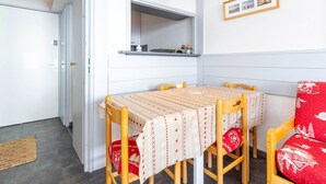 Een kleine keuken met een eettafel, stoelen, een hanglamp en een ingelijste foto aan de muur.