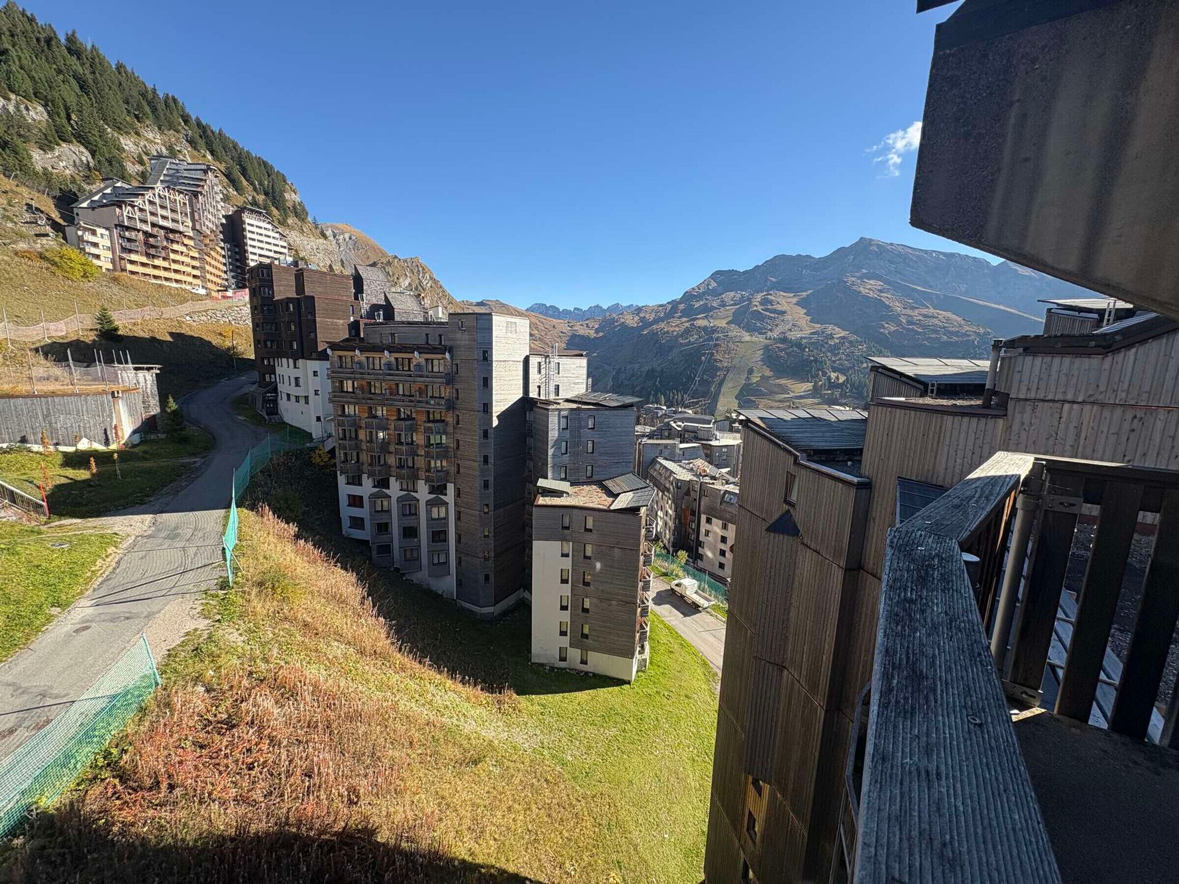 Vista des d'una collada d'un hotel amb diversos edificis, un camí sinuós i muntanyes al fons.