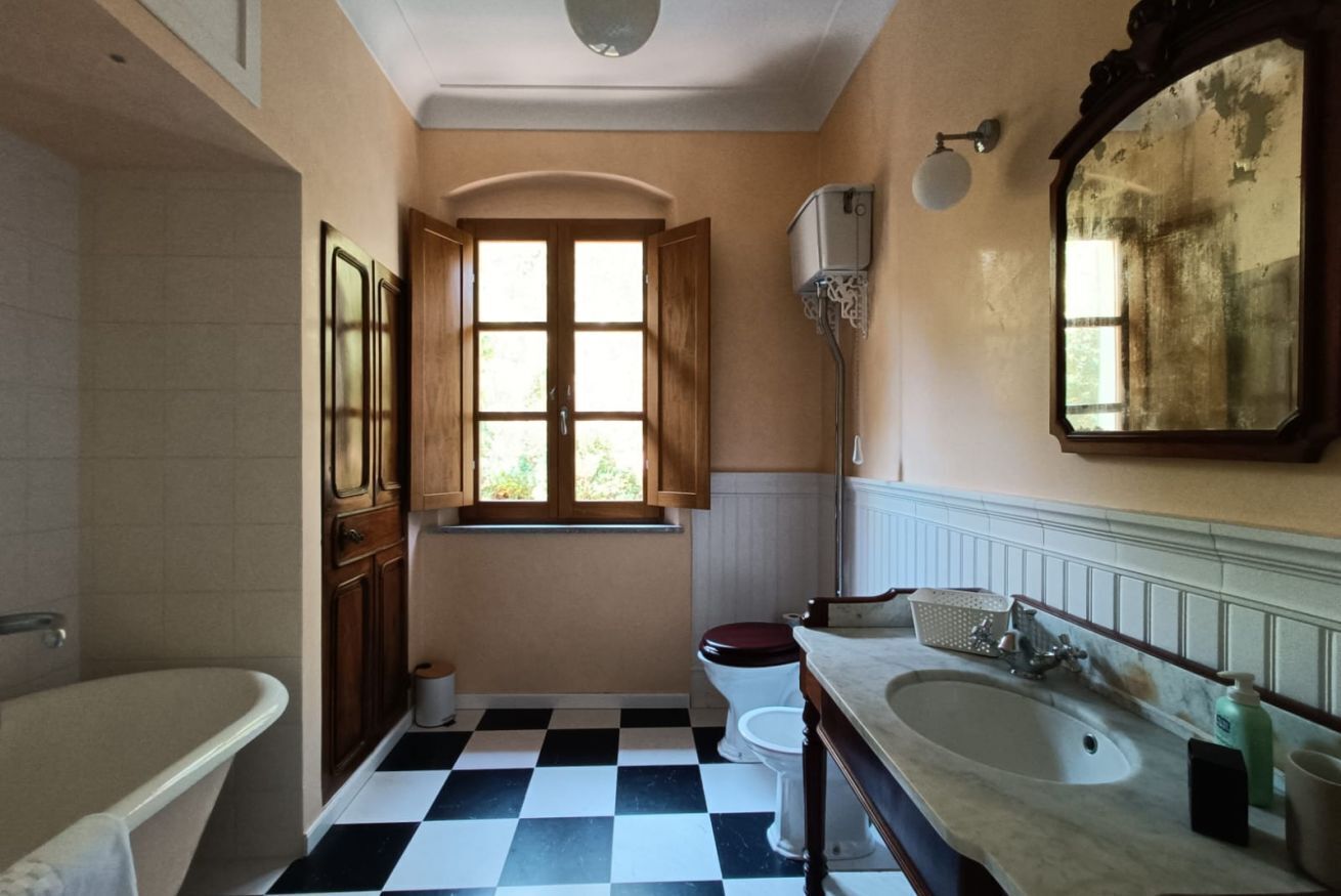 Ein Badezimmer mit Schachbrettfußboden, einer Badewanne, einer Toilette und einem Waschbecken.