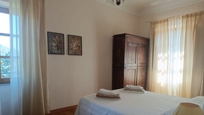 Une chambre à coucher avec un lit, une armoire en bois et deux tableaux floraux accrochés au mur.