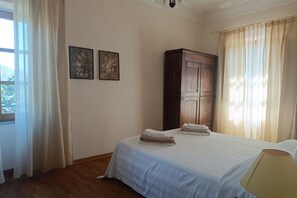 Une chambre à coucher avec un lit, une armoire en bois et deux tableaux floraux accrochés au mur.
