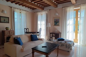 A furnished living room with a sofa, a coffee table, a bed, and a dining area. - Villa Aurora with Private Pool (Porto Azzurro)