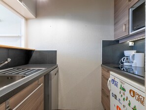 A compact kitchen with a sink, dishwasher, and a refrigerator with stickers. - Modern apartment, station view - 4/5 guests (Avoriaz)