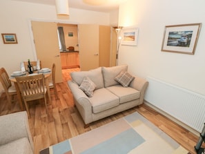 A cozy living room with a sofa, a dining table with chairs, a radiator, and a framed picture on the wall.