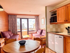 A cozy room with a dining table, chairs, a sofa, a kitchen with wooden cabinets, a microwave, and a dishwasher. - Peaceful studio near shops - 4 guests (Avoriaz)