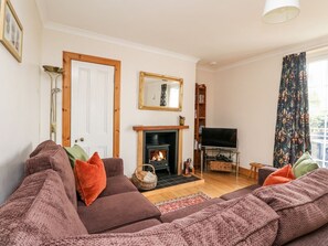 A living room with a sofa, fireplace, television, and a bookshelf.