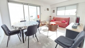 Een moderne woonkamer met een ronde tafel, stoelen, een bank en een televisie.